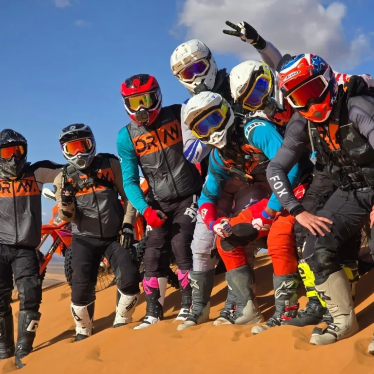 Enduro Experiences riders posing together on a Sahara dune